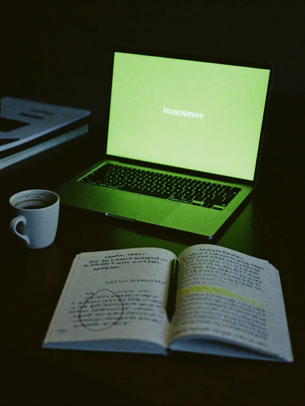 Arbeitsplatz in der Agentur: Laptop, Notizbuch und Kaffee im dunklen Studio