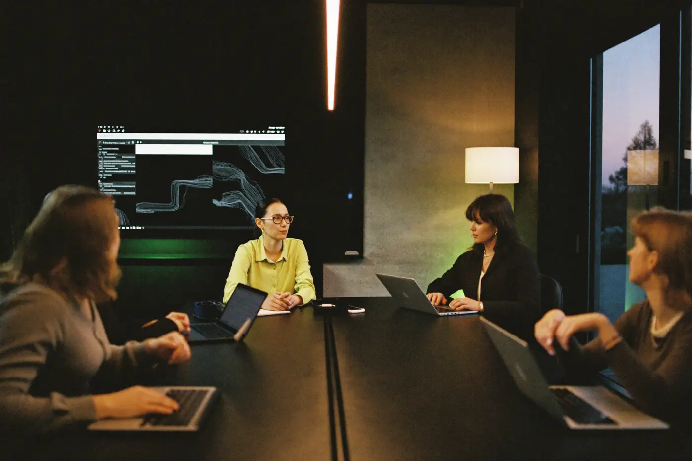 Das Team der Plusagentur bei der Arbeit am Konferenztisch, im Hintergrund ein Screen mit Auswertungen